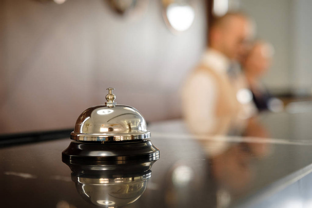 Modern luxus Hotel recepciós pult íróasztal Bell. Szolgáltatás Bell helyüket a recepción. Ezüst Call Bell, asztalra, recepciós, a háttérben. fene Hotel. Koncepció. - Fotó, kép