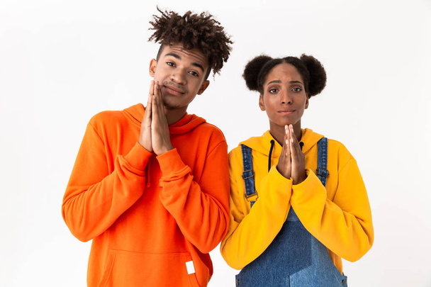 Image of african american couple in colorful clothes holding palms together for pray isolated over white background - Fotoğraf, Görsel