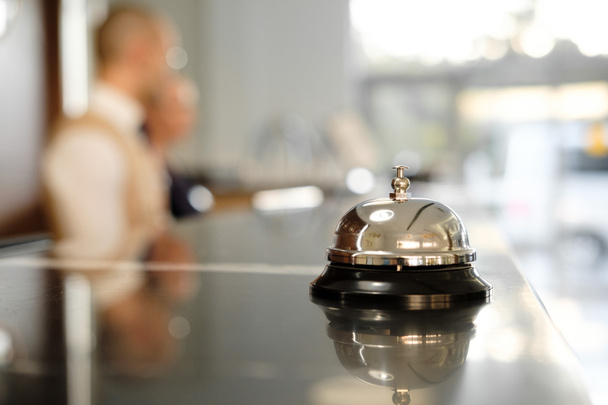Modern luxus Hotel recepciós pult íróasztal Bell. Szolgáltatás Bell helyüket a recepción. Ezüst Call Bell, asztalra, recepciós, a háttérben. fene Hotel. Koncepció.  - Fotó, kép