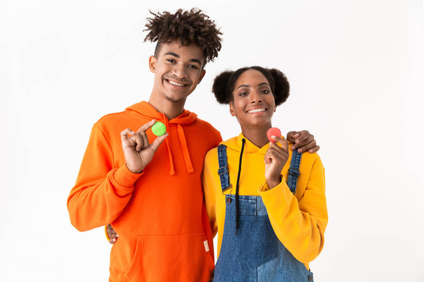 Photo of african american students in colorful clothes holding macaroon biscuits isolated over white background - Foto, afbeelding