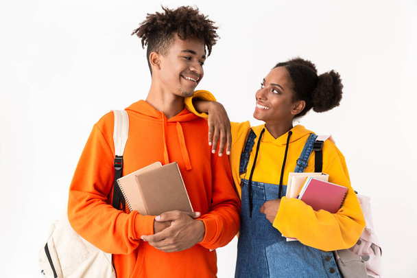 Photo of african american friends wearing backpacks holding exercise books isolated over white background - Фото, изображение