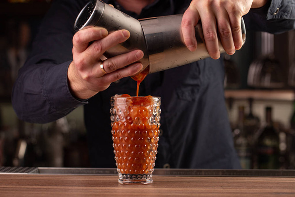 bartender pours tomato red juice from the shaker, making a cocktail, drink at the bar counter - Photo, Image