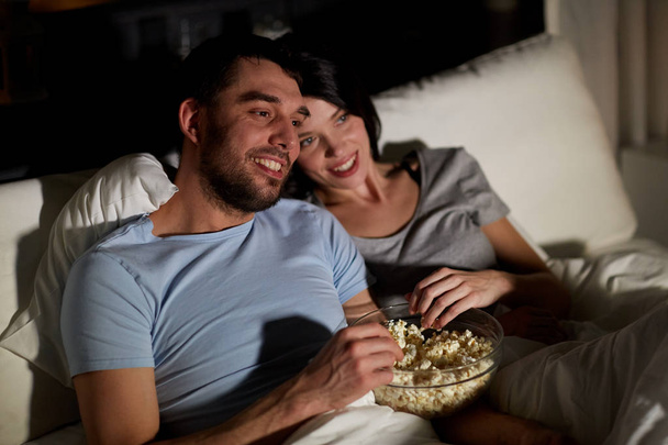 couple with popcorn watching tv at night at home - Φωτογραφία, εικόνα