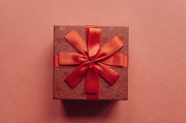 Red box with a bow with a gift on a red background - Foto, imagen
