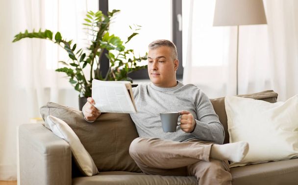 man reading newspaper and drinking coffee at home - Photo, Image