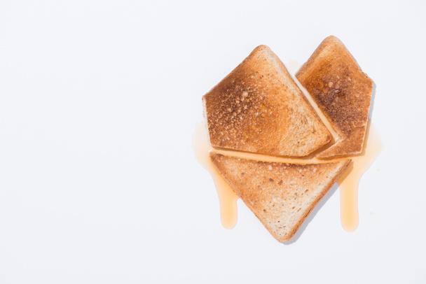 bovenaanzicht van hart vorm gemaakt van toast met stroop op witte ondergrond - Foto, afbeelding
