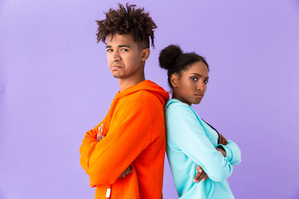 Photo of displeased african american couple in colorful clothes standing back to back isolated over violet background - Fotoğraf, Görsel