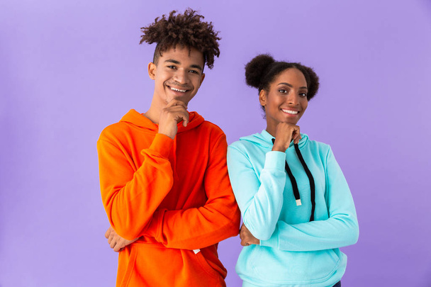 Photo of african american couple in colorful clothes smiling and touching chins isolated over violet background - Fotografie, Obrázek
