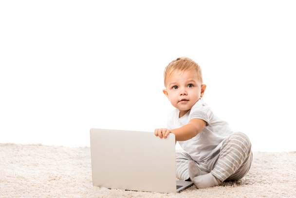 cute toddler boy sitting at laptop on carpet isolated on white - Photo, Image