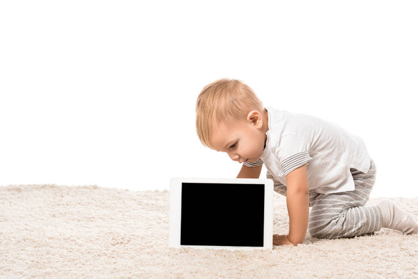 μικρό παιδί αγόρι κάθεται στο χαλί και βλέπουν ψηφιακή δισκίο που απομονώνονται σε λευκό - Φωτογραφία, εικόνα