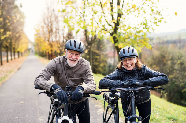Active senior couple with electrobikes standing outdoors on a road in nature. - Fotó, kép
