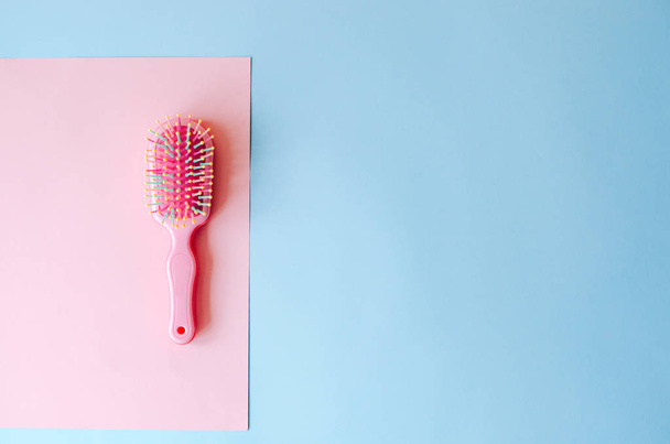 Pink hairbrush on a pink-blue background. - Φωτογραφία, εικόνα