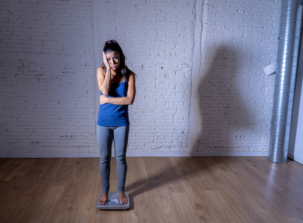 Jonge pasvorm en slanke vrouw controleren lichaamsgewicht op schaal vinden zichzelf vet en gevoel depressief en wanhopig in bij gebreke dieet eetstoornis en dieting concept. - Foto, afbeelding