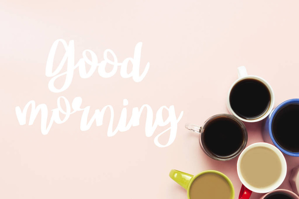 Sporo wielokolorowe filiżanki kawy i napoje kawa na różowym tle z dzień dobry tekst. Koncepcja śniadanie z kawą, Kawa z przyjaciółmi. Widok płaski świeckich, top. - Zdjęcie, obraz