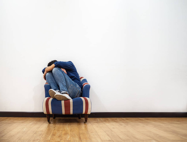 Мужчина обнимает колени и плачет на диване
 - Фото, изображение