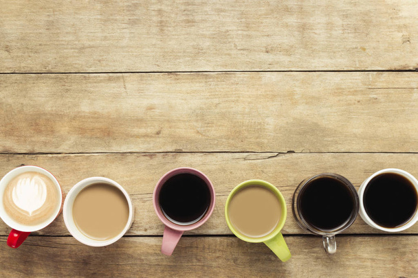 Wiele wielobarwny filiżanek kawy a Kawa napoje ustawieni na podłoże drewniane. Koncepcja śniadanie z kawą, Kawa z przyjaciółmi. Widok płaski świeckich, top. - Zdjęcie, obraz