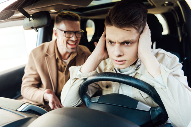 irritado padre gritándole a hijo adolescente en coche
 - Foto, Imagen