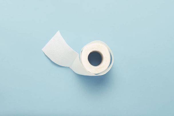 Roll of unfolded toilet paper on a blue background. Flat lay, top view. - Фото, зображення