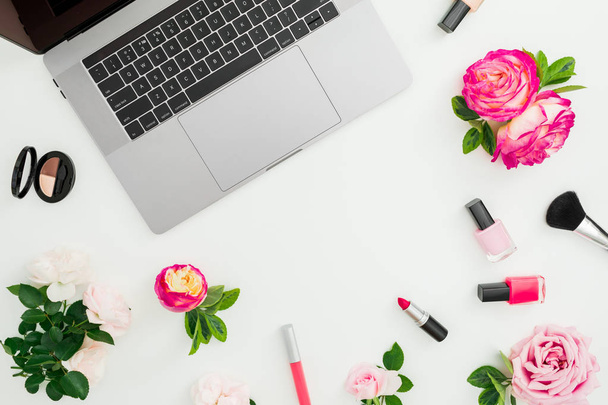 Laptop, roses flowers, cosmetics isolated on white background. Flat lay. Top view. Feminine composition with copy space - Фото, изображение