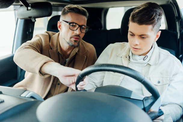 handsome father teaching teen son driving car - Fotoğraf, Görsel