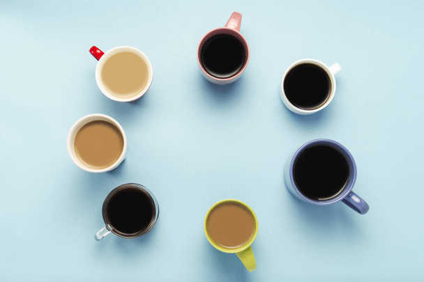 Mnoho vícebarevné šálky kávy a kávové nápoje na modrém pozadí. Tvar kruh. Koncept snídani s kávou, kávou s přáteli. Plochá ležel, horní pohled. - Fotografie, Obrázek