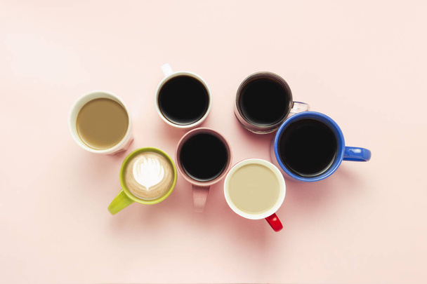 Багато різнокольорових чашок кави та кавових напоїв на рожевому фоні. Концептуальний сніданок з кавою, кава з друзями. Плоский прошарок, вид зверху
. - Фото, зображення