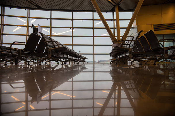 Sala de embarque no aeroporto. Janelas grandes. Clima nublado
 - Foto, Imagem