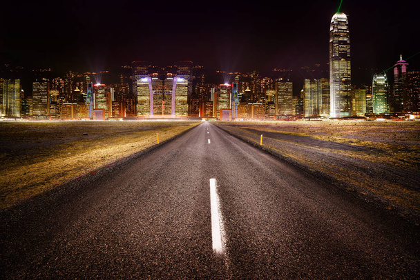 Estrada vazia à noite com luzes da cidade ao fundo
 - Foto, Imagem