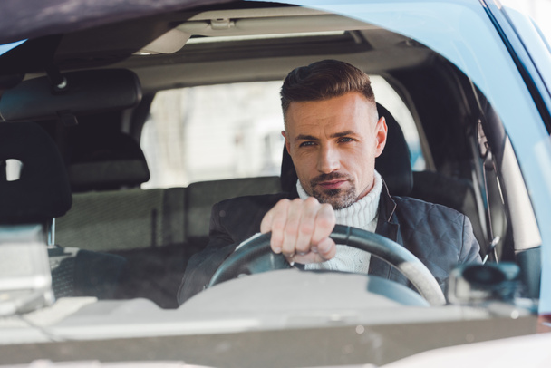 Handsome man sitting in car and holding steer - 写真・画像