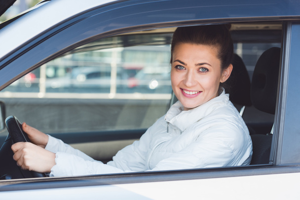 Beautiful woman sitting in car and holding steering wheel  - Zdjęcie, obraz