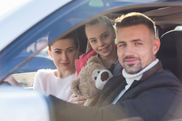  Preteen daughter sitting in car with teddy bear and parents - Photo, image