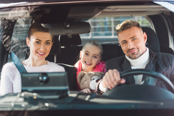  Preteen daughter sitting in car with teddy bear and smiling with parents - Foto, Bild