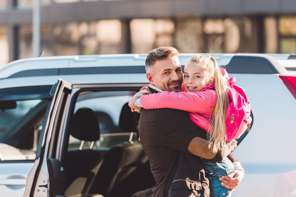 Father holding daughter and standing near car - Foto, immagini