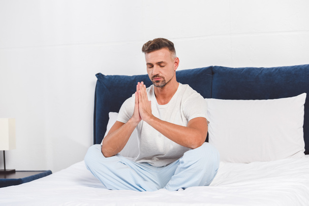 Knappe man beoefenen van yoga op bed - Foto, afbeelding