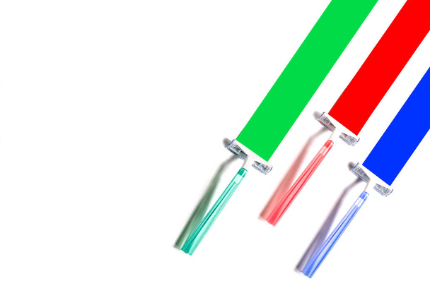 Três lâminas de barbear multicoloridas deixam marcas no papel em forma de listras coloridas. Conceito de cor inesperado mínimo
 - Foto, Imagem