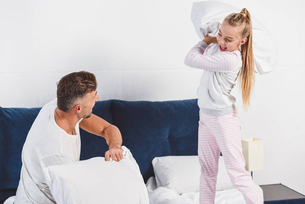 Father and daughter having pillow fight at home - Foto, Imagem