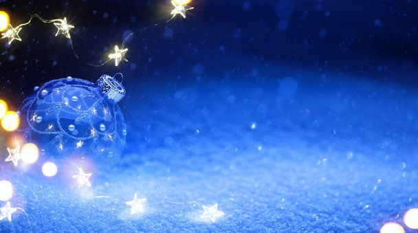 Свет елки и праздничные украшения на синем фоне снега
 - Фото, изображение