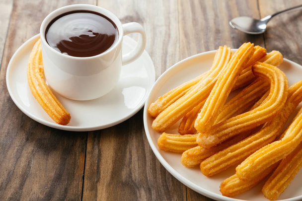 Traditional spanish churros with hot chocolate sauce on a rustic wooden table - Photo, Image