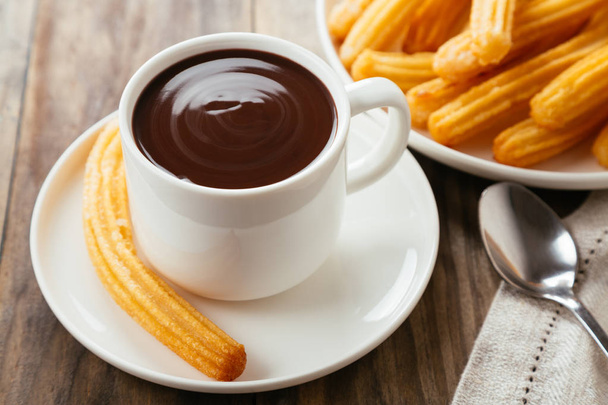 Traditional spanish churros with hot chocolate sauce on a rustic wooden table - Photo, Image