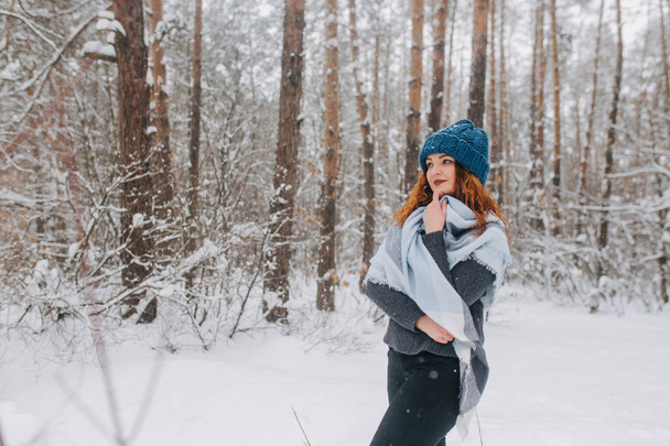 Girl in a hat and a sweater in the forest with snow - Photo, Image