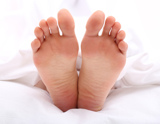 Beautiful feet of a young woman lying in bed close up - Foto, imagen