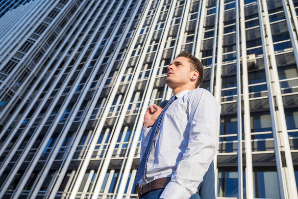 Businessman in classy suit holding his jacket on background of modern office skyscraper. - Fotoğraf, Görsel
