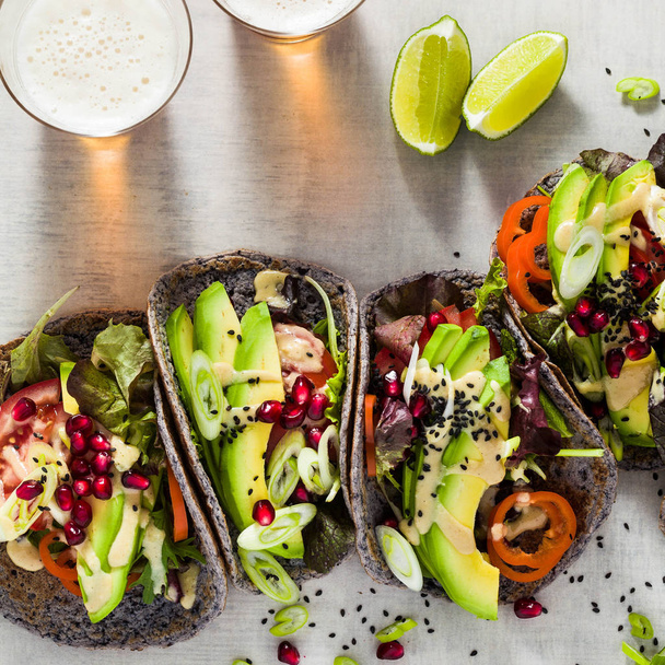 Gluten-free vegan tacos from black bean  with tomato and avocado salad  with tahini sauce and pomegranate seeds. healthy fast food for the whole family or party and beer - Photo, image