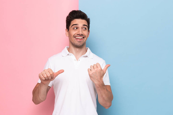 Image of optimistic man 30s having stubble pointing fingers aside at copyspace isolated over colorful background - Foto, afbeelding