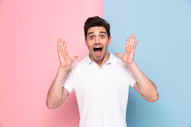 Image of excited man 30s having stubble screaming and raising arms isolated over colorful background - Foto, afbeelding