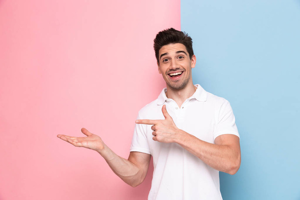 Image of handsome man 30s having stubble pointing fingers aside at copyspace isolated over colorful background - Foto, afbeelding