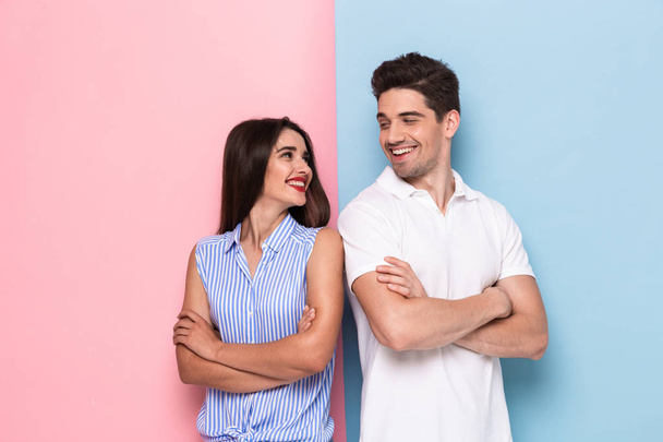 Образ щасливого чоловіка і жінки в повсякденному одязі, що стоїть з обіймами, схрещеними ізольовано на барвистому фоні
 - Фото, зображення