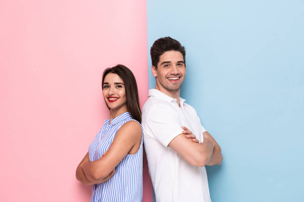 Image of european man and woman in casual wear standing back to back with arms crossed isolated over colorful background - Фото, изображение