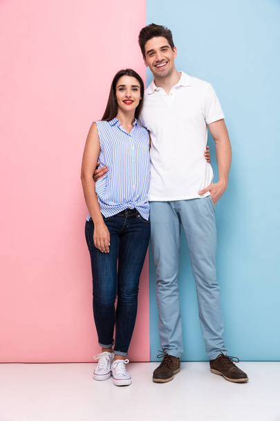 Full length image of european man and woman in casual wear hugging and smiling together isolated over colorful background - Foto, afbeelding