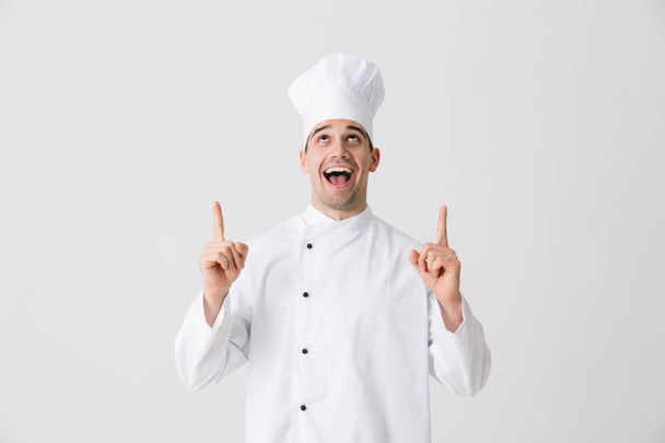 Image of handsome excited young man chef indoors isolated over white wall background pointing. - Φωτογραφία, εικόνα